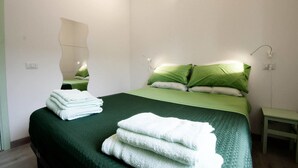 A neatly made bed with green bedding and white towels, a bedside table, and a wall-mounted light fixture. - B&B La Rosa di Orvieto (Orvieto)