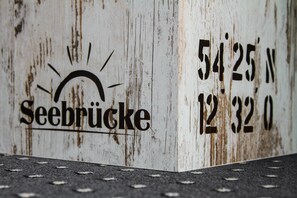 A weathered sign with the text "Seebrücke" and coordinates "54°25'N 12°32'0"E. - Hotel Seebrücke (Zingst)