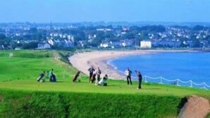 Un campo de golf costero con playa de arena y vista despejada al mar.