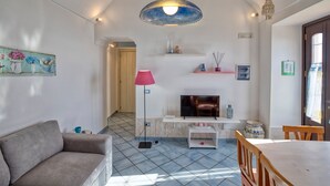Ein Wohnzimmer mit einer Couch, Fernseher und einem Essbereich mit Tisch und Stühlen.