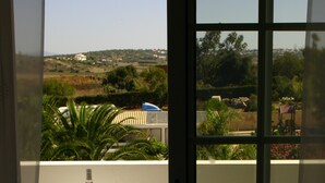 A balcony with a table set for two, a bottle of red wine, and two wine glasses.