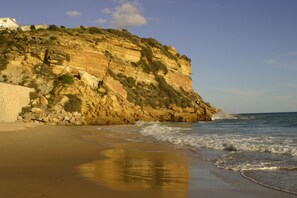 Un paysage côtier avec une falaise rocheuse et une plage de sable.