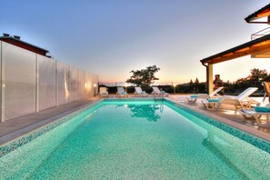Relax by the serene pool surrounded by a low deck and a glass-enclosed structure.