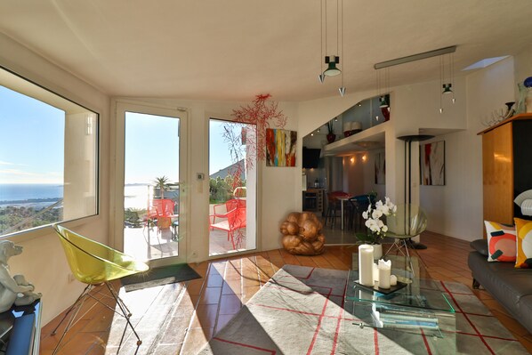 Un salón amplio con una mesa de cristal grande, una silla amarilla y vistas al exterior.