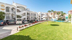 Un hotel con edificios blancos, piscina y césped bien cuidado.