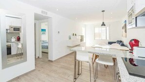 Una cocina moderna con una isla central, electrodomésticos de acero inoxidable y una zona de comedor con taburetes de bar.