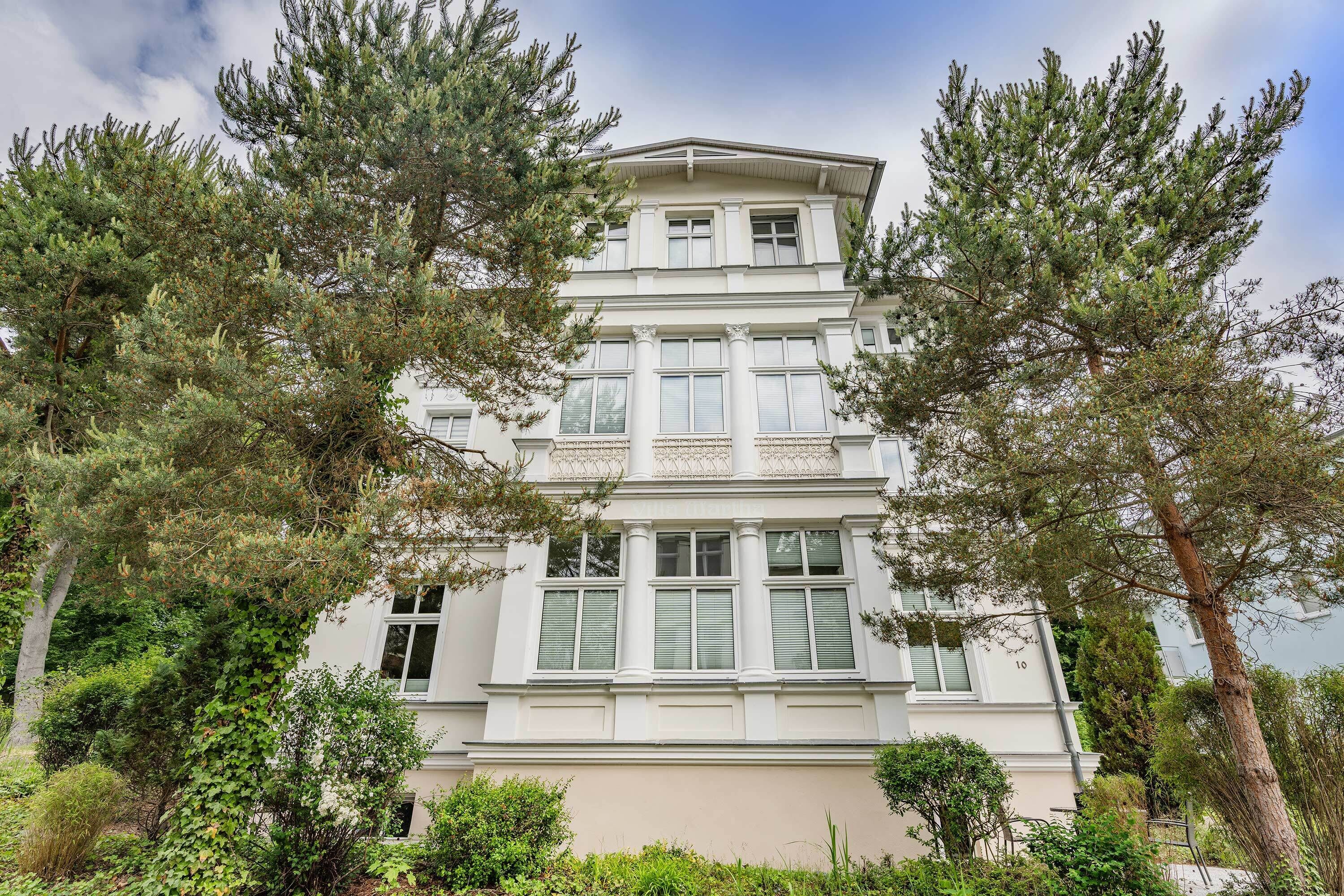 Un immeuble à étages doté d’une façade symétrique, de grandes fenêtres et d’un balcon à l’étage supérieur.