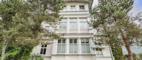 A multi-story building with a symmetrical facade, large windows, and a balcony on the upper floor.