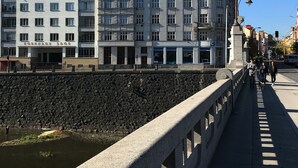 Un pont en pierre, avec un mur en pierre d’un côté et une rangée de bâtiments dotés de nombreuses fenêtres et de balcons de l’autre.