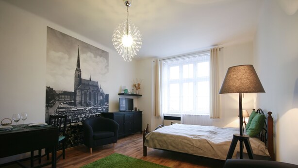 Une chambre à coucher avec un lit, un bureau, une chaise, une lampe et un tapis vert.