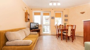 A living room with a sofa, TV, dining table, chairs, and a wooden cabinet.