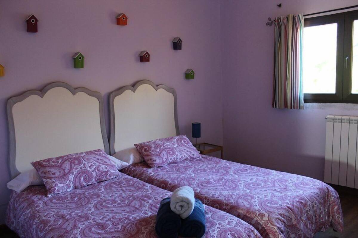 Un dormitorio con dos camas, cada una con cabecera, y un ventanal con cortinas.