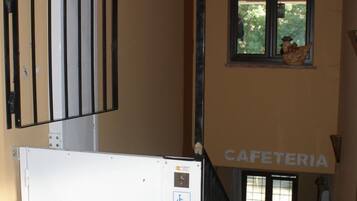 Una escalera con barandilla, una puerta blanca con el símbolo de accesibilidad para sillas de ruedas y una ventana decorada con un gallo.