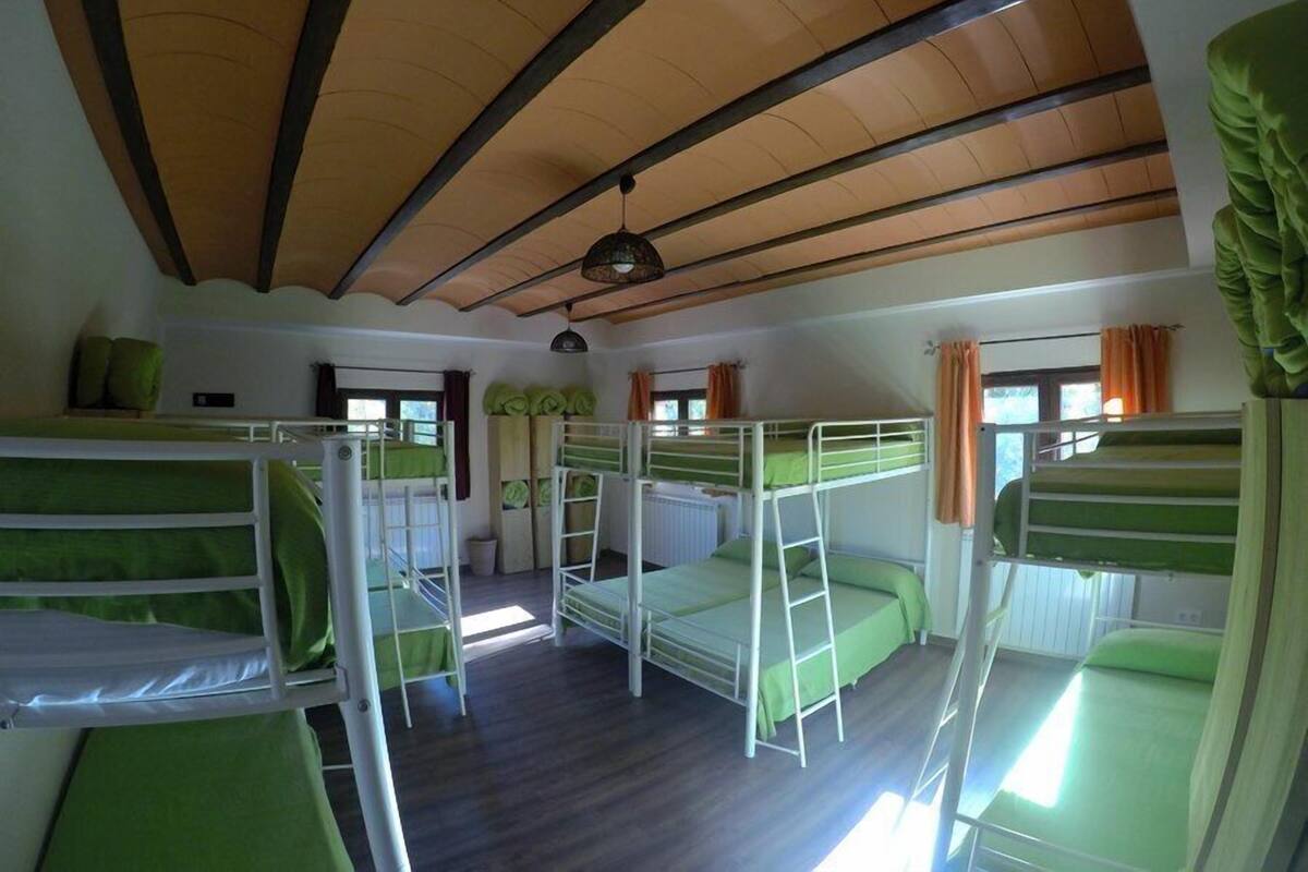 Un dormitorio con literas, vigas de madera en el techo y una ventana con cortinas.