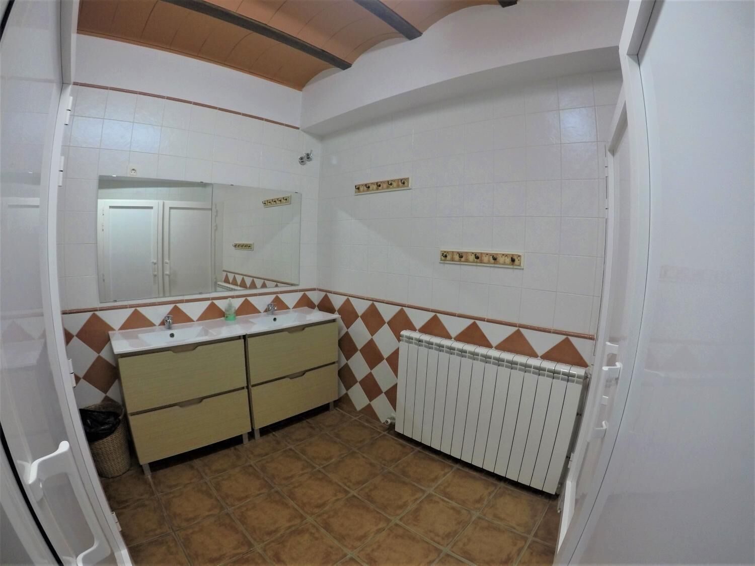 Un baño con un lavamanos blanco, dos armarios, un espejo y un radiador.