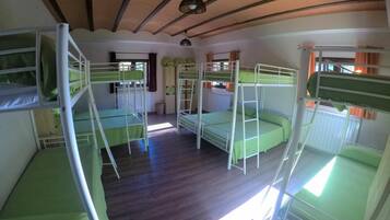 Un dormitorio con literas, piso de madera y techo inclinado.