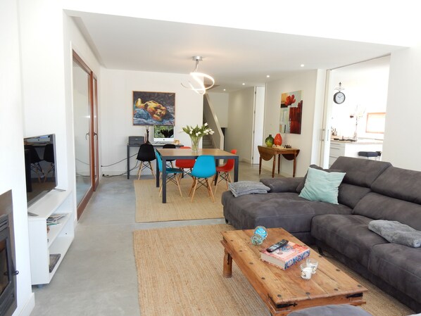 Una sala de estar moderna con un sofá gris, una mesa de centro de madera y una zona de comedor con una mesa y sillas.