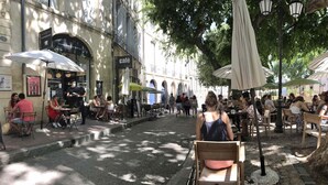 An outdoor café area with tables and chairs under umbrellas, surrounded by buildings with shops and signs. - Apartment with cathedral view in the historical quarter  (Montpellier)