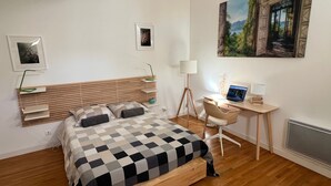 A bedroom with a bed, a desk, and a chair. There is a lamp, a laptop, and a picture on the wall. - Apartment with cathedral view in the historical quarter  (Montpellier)