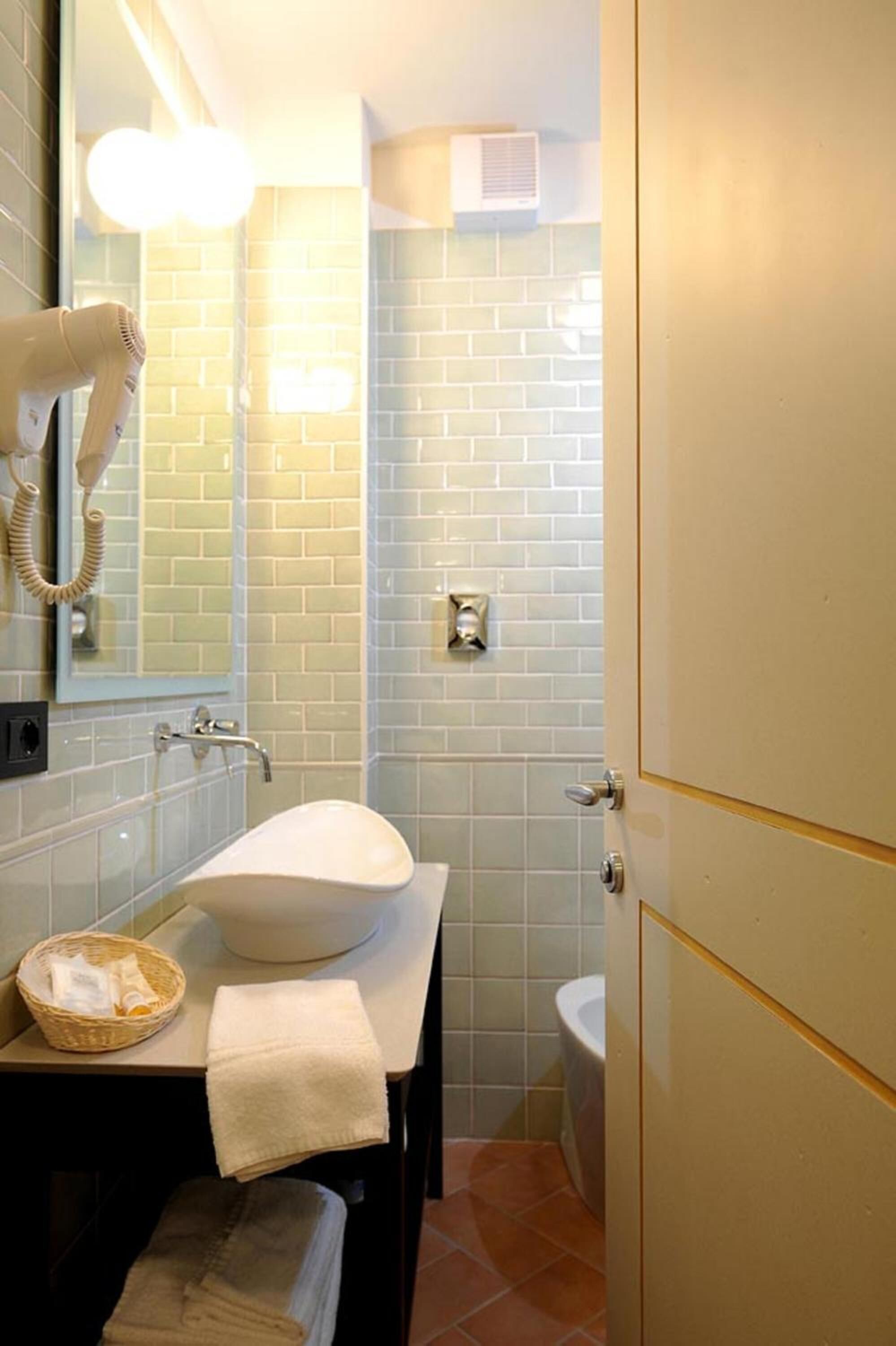 A bathroom with a white sink, a hairdryer, and a mirror.