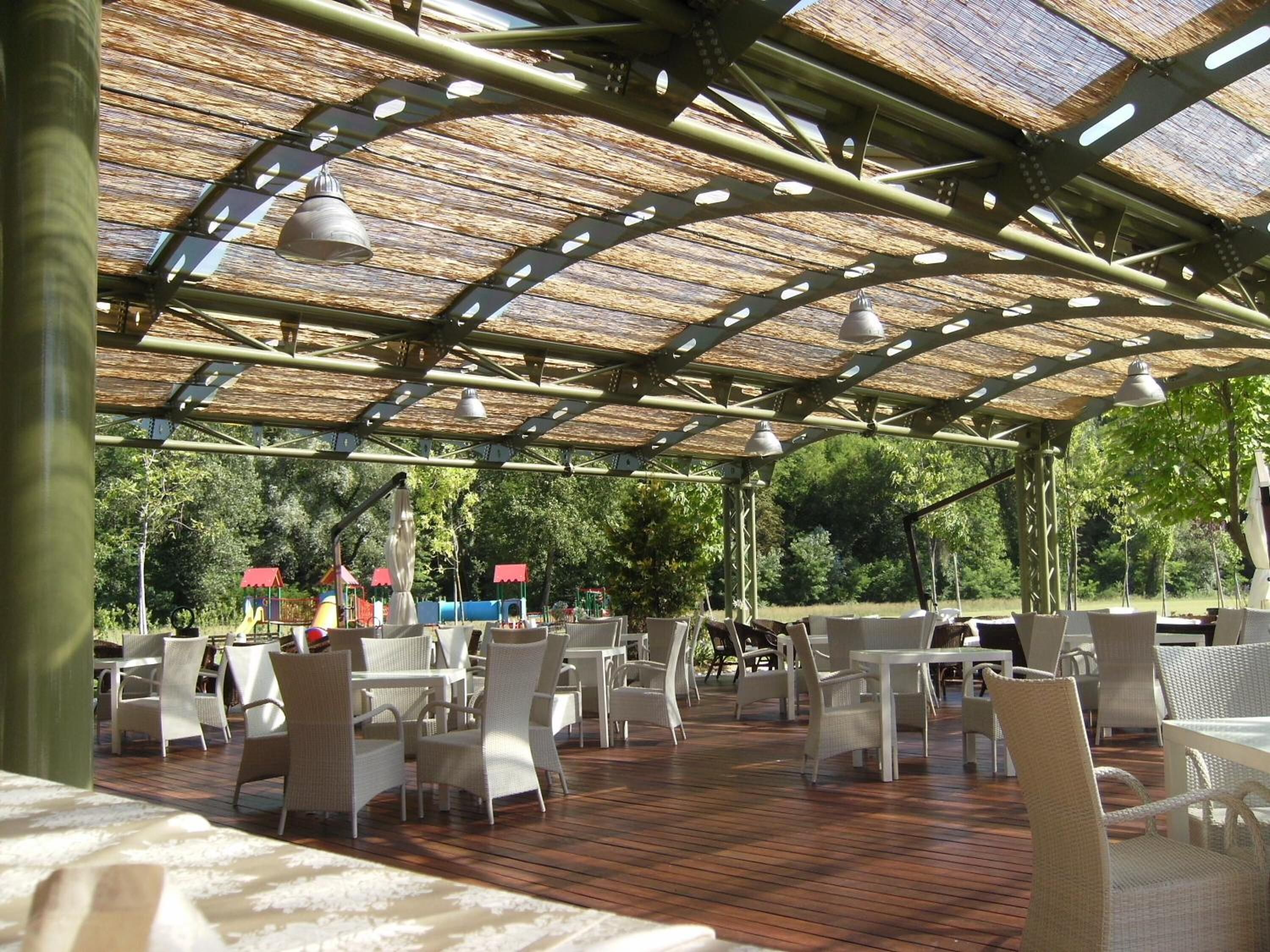 An outdoor patio with wicker furniture and a thatched roof structure.