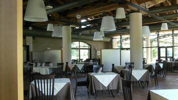 Un espace de restauration intérieur avec des tables et des chaises, de grandes suspensions et un plafond en bois rustique.
