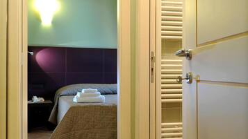 Une chambre d’hôtel avec un lit, une table de chevet avec un téléphone et un luminaire fixé au mur.