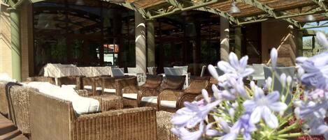 Un espace extérieur aménagé avec des meubles en osier et une structure en forme de pergola.