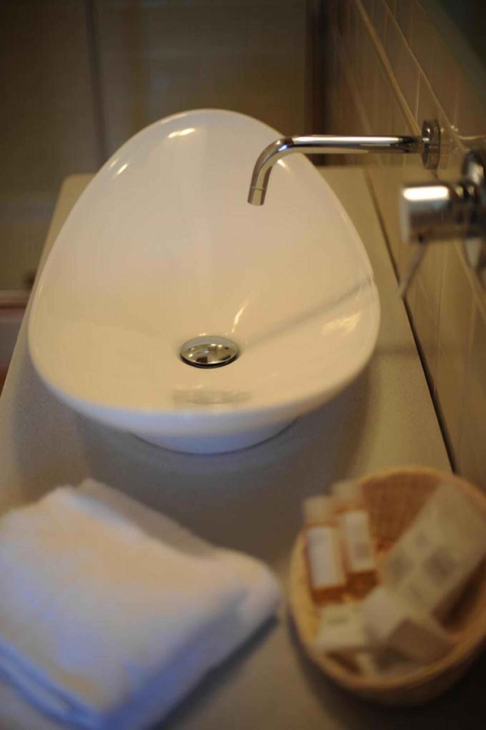 Un bany amb un lavabo blanc, una tovallola i un recipient amb productes de tocador.
