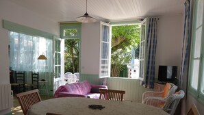 A dining area with a round table, chairs, a sofa, and a television.