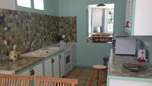 A kitchen with a tiled backsplash, wooden chairs, a sink, and a refrigerator.