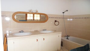 Un baño con dos lavamanos, un espejo grande, una ducha y un aro para toallas.
