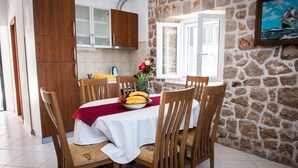 A dining area with a table set for four, surrounded by wooden chairs, a red tablecloth, and a fruit bowl. - Luxury stone house with private pool, complete privacy in a relaxing atmosphere (Kremena)