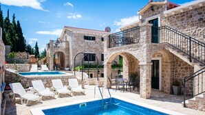 A stone building with a swimming pool, outdoor seating, and a staircase. - Luxury stone house with private pool, complete privacy in a relaxing atmosphere (Kremena)