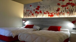 Una habitación de hotel con dos camas, cada una con ropa de cama roja y blanca, y un mural grande de flores rojas en la pared.