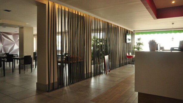 Un moderno vestíbulo de hotel con mostrador de recepción, zona de estar y un panel decorativo vertical.
