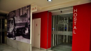 Un vestíbulo de hotel con una pared roja y puerta de cristal.
