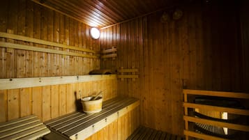 A sauna with wooden benches and a bench seat, a wooden bench with a bucket and a spoon, and a wooden bench with a bench seat.
