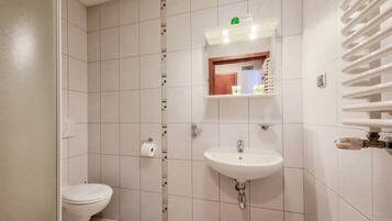 Un baño con inodoro, lavamanos y un perchero para toallas.