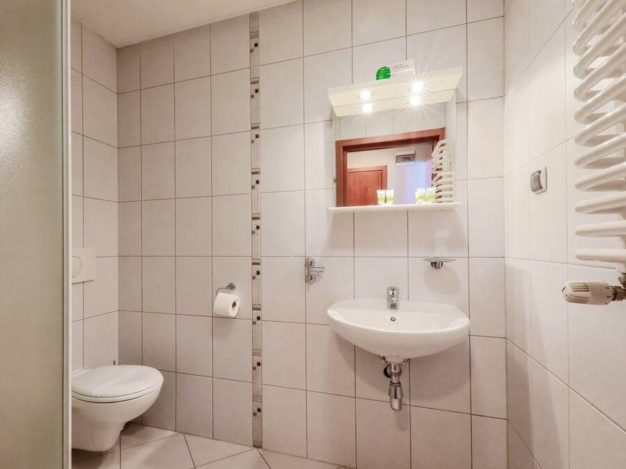 Un baño con inodoro, lavamanos y un perchero para toallas.