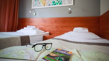 Habitación de hotel con dos camas, un mapa y un par de gafas sobre la cama.