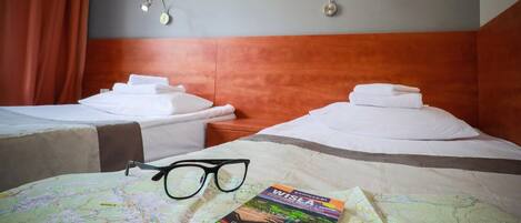 Habitación de hotel con dos camas, un mapa y un par de gafas sobre la cama.