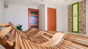 Quarto com um banco de madeira, porta com painéis de vidro jateado e parede decorada com toras empilhadas.