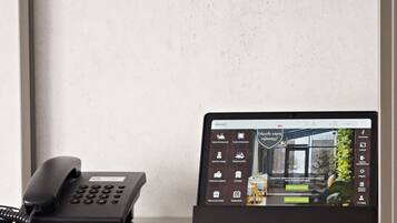 Mostrador de recepción de un hotel con un teléfono tradicional y una pantalla digital que muestra la página web del hotel.