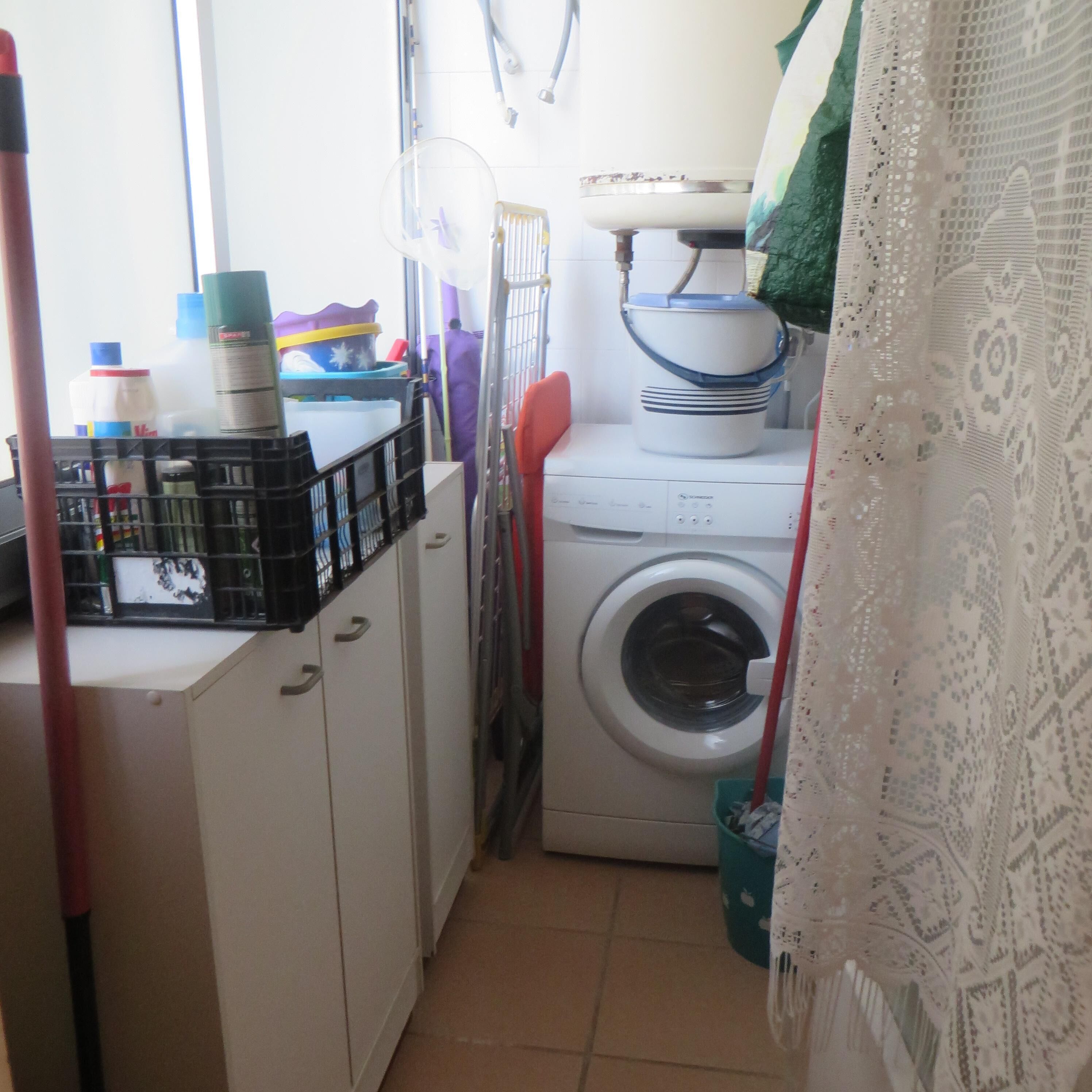 Un espace buanderie comprenant un lave-linge, un étendoir et un meuble avec des bacs de rangement.