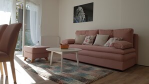 A living room with a pink sofa, a white coffee table, and a colorful rug.