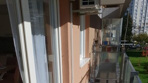 A balcony with a glass door, a small table, and a chair.