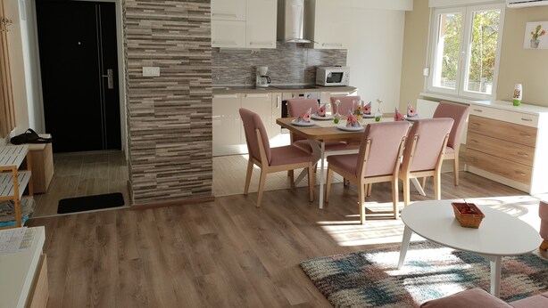 A modern kitchen with white cabinets, a built-in microwave, and a dining area with pink chairs and a white table.