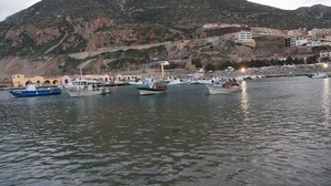 A marina with boats docked, a mountainous backdrop, and buildings on the hillside. - Stylishly designed apartment with magnificent sea views in a stunning natural environment (Portixeddu)
