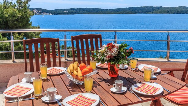 Ein Tisch ist für das Frühstück gedeckt, mit Blick auf einen See und Hügel.